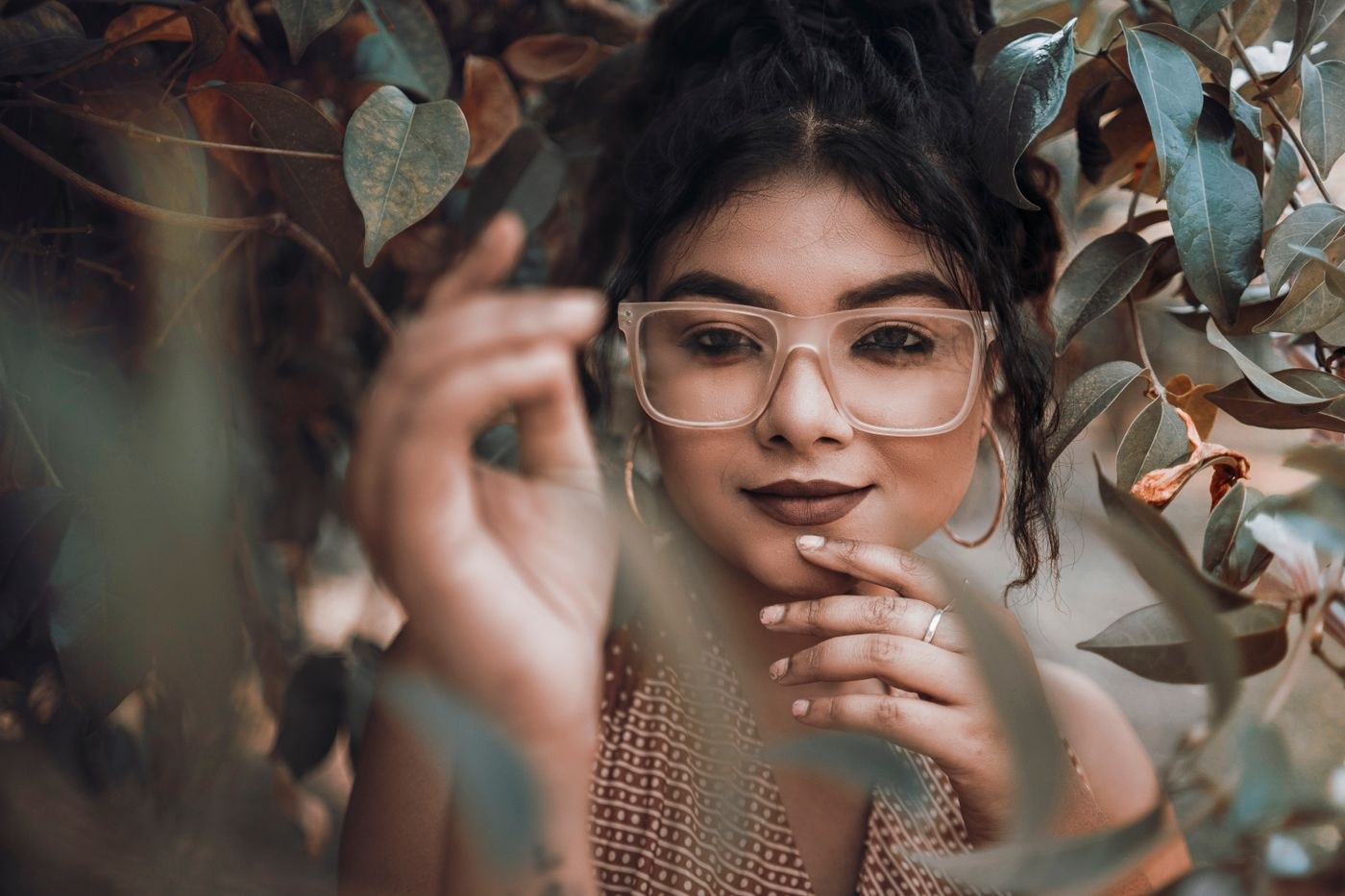 Woman looking through foreground leaves