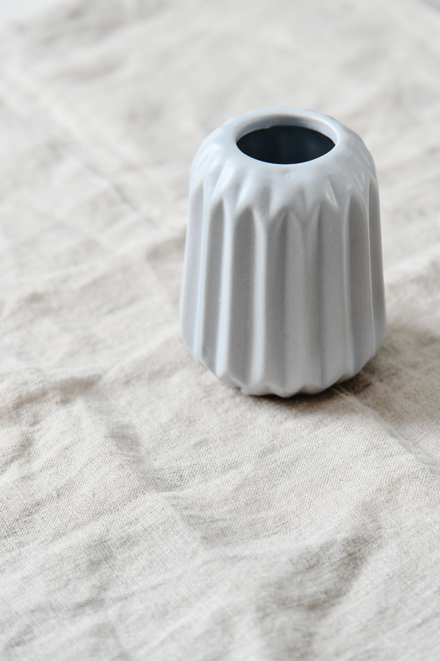 White ribbed vase on pale textured fabric