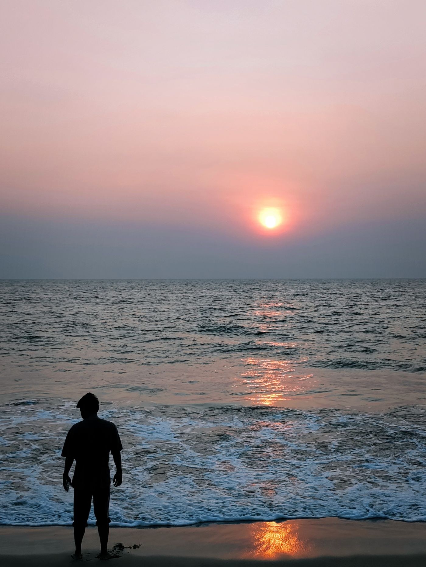 Person silhouetted against the sea at sunset