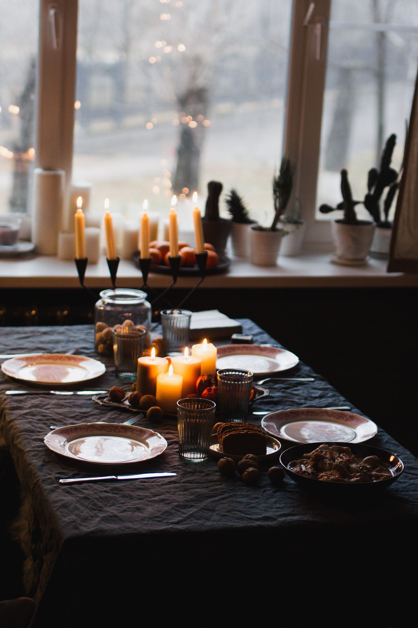 Candles illuminating a table set beside a window