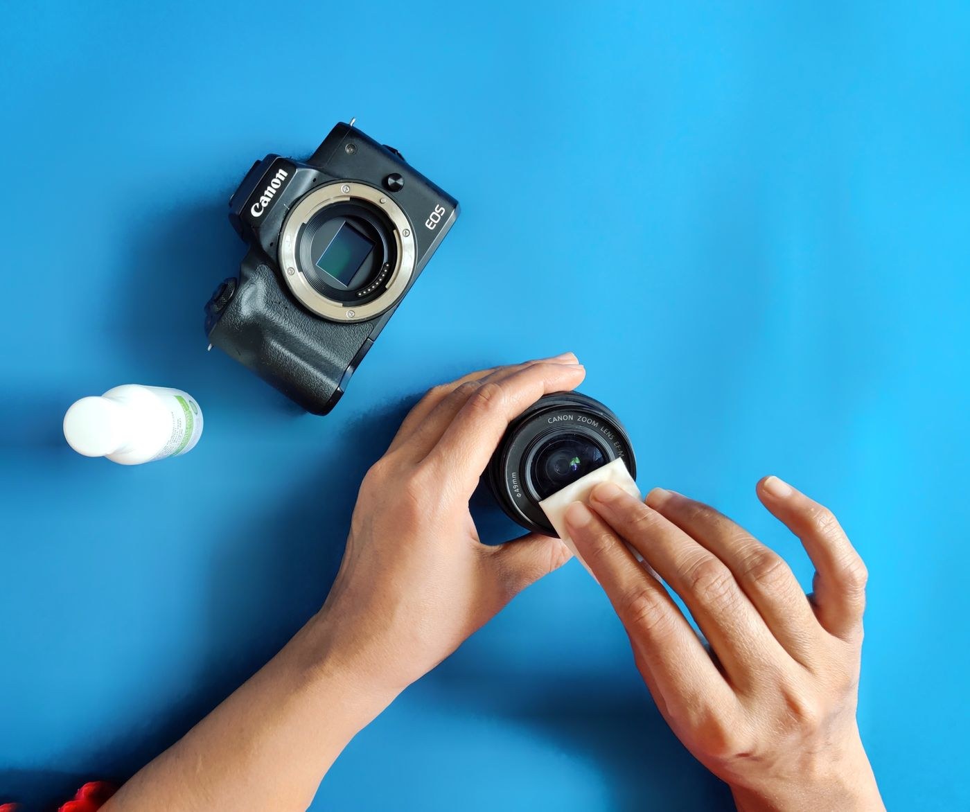 Hands cleaning a lens on a blue surface