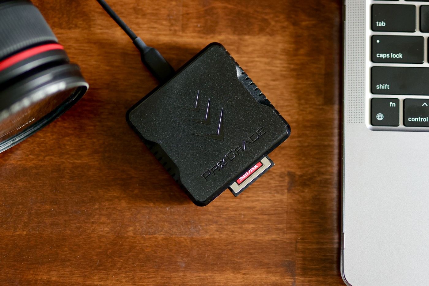 Memory card reader beside a laptop and lens