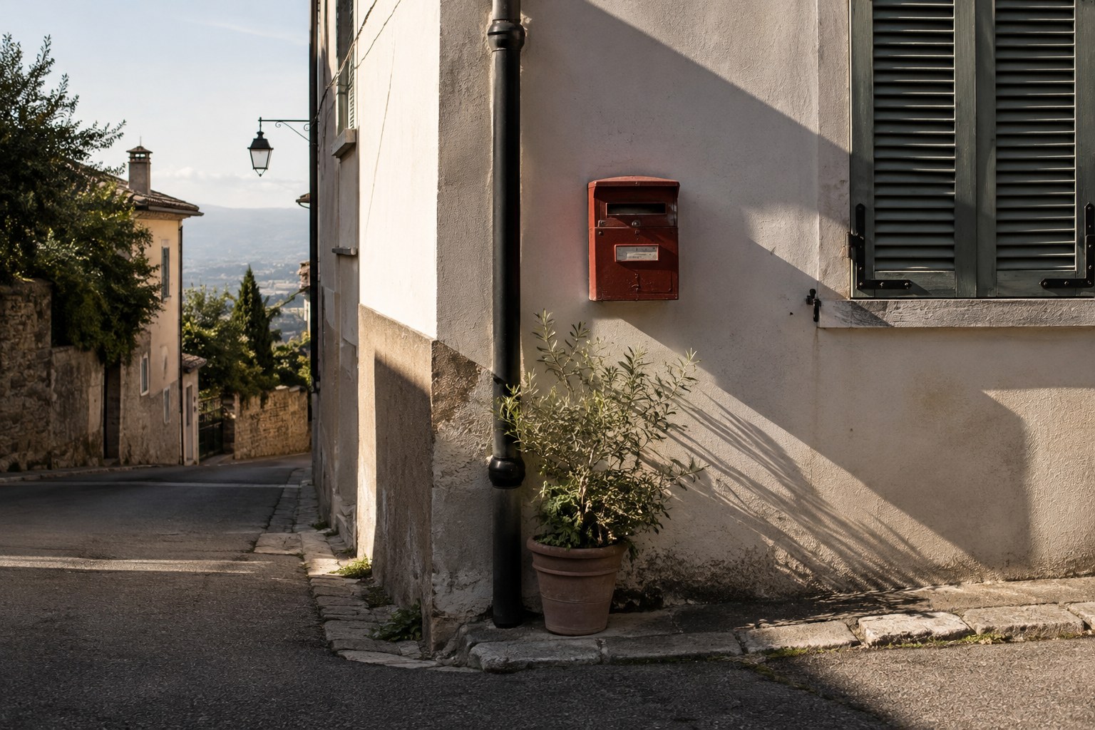 Afternoon shadows across a wall with a red mailbox