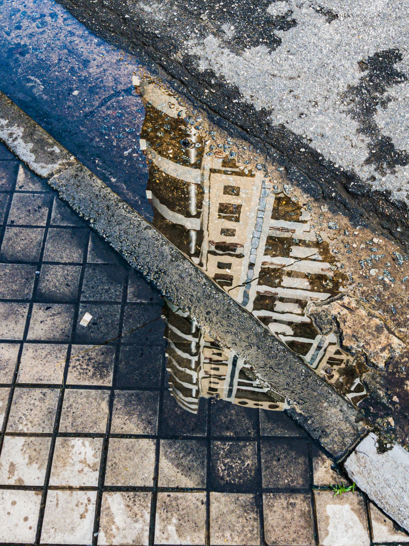 Building reflected in a puddle on paving stones