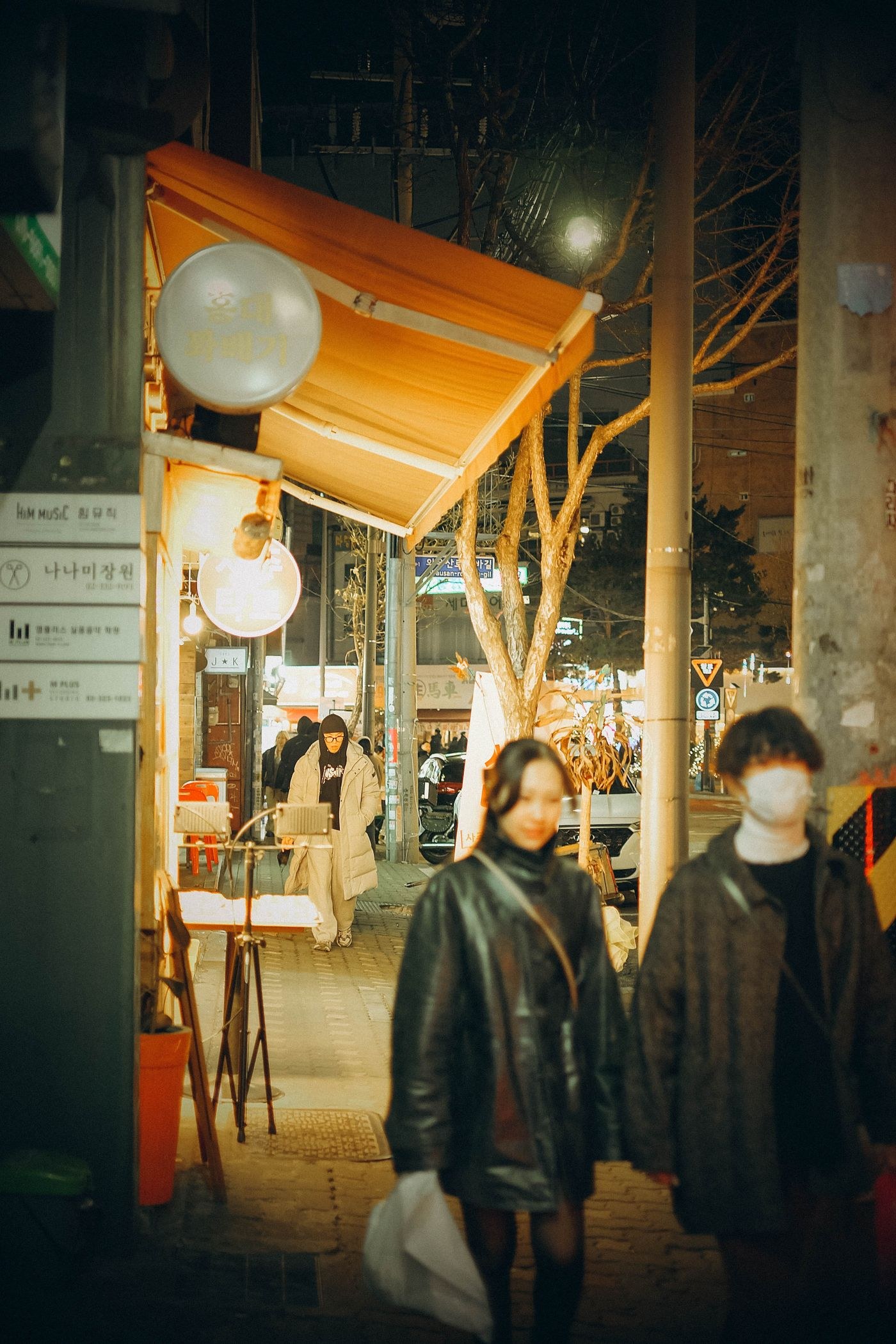 People passing illuminated storefronts at night