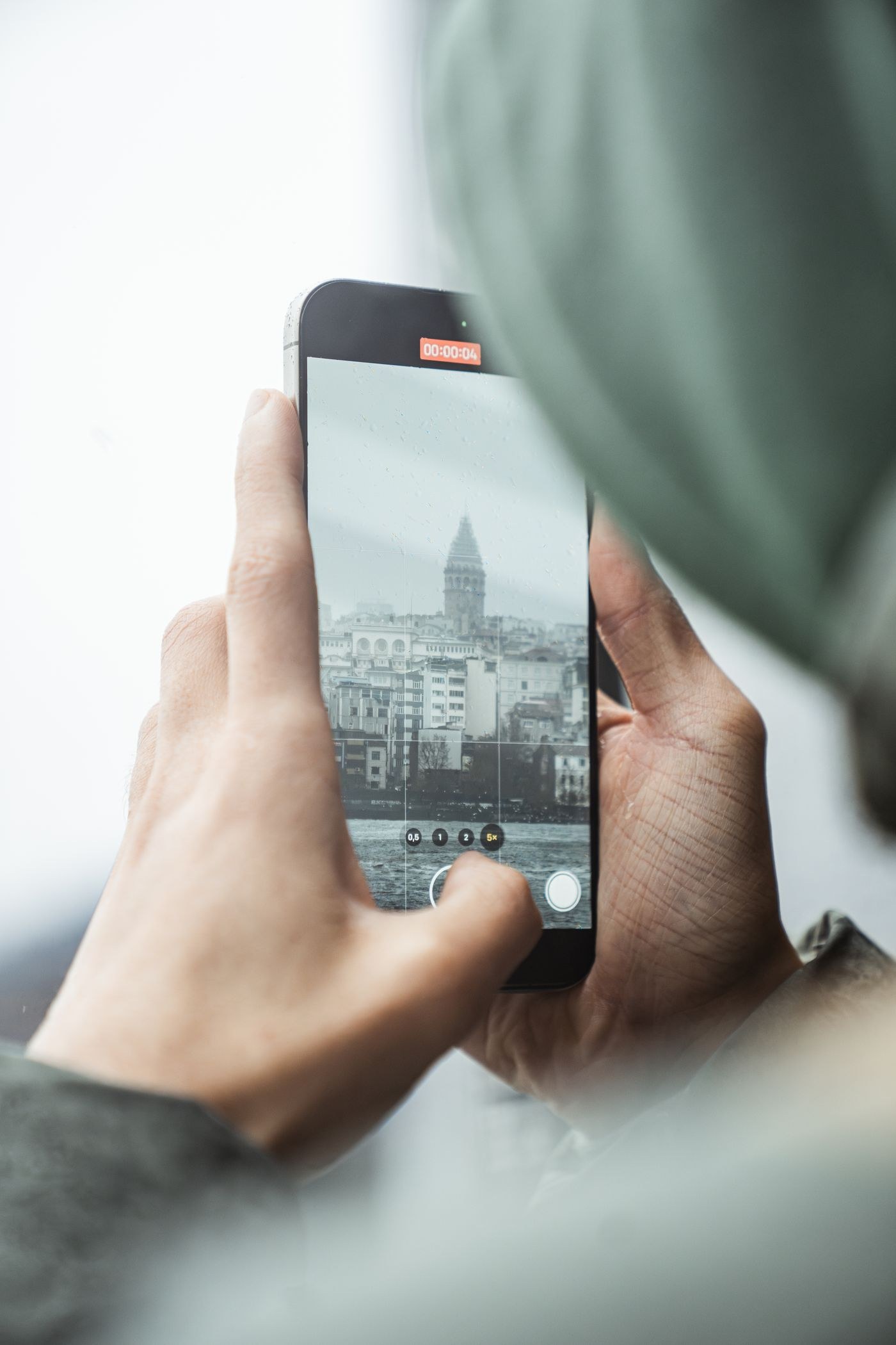 Hands photographing a tower with a smartphone