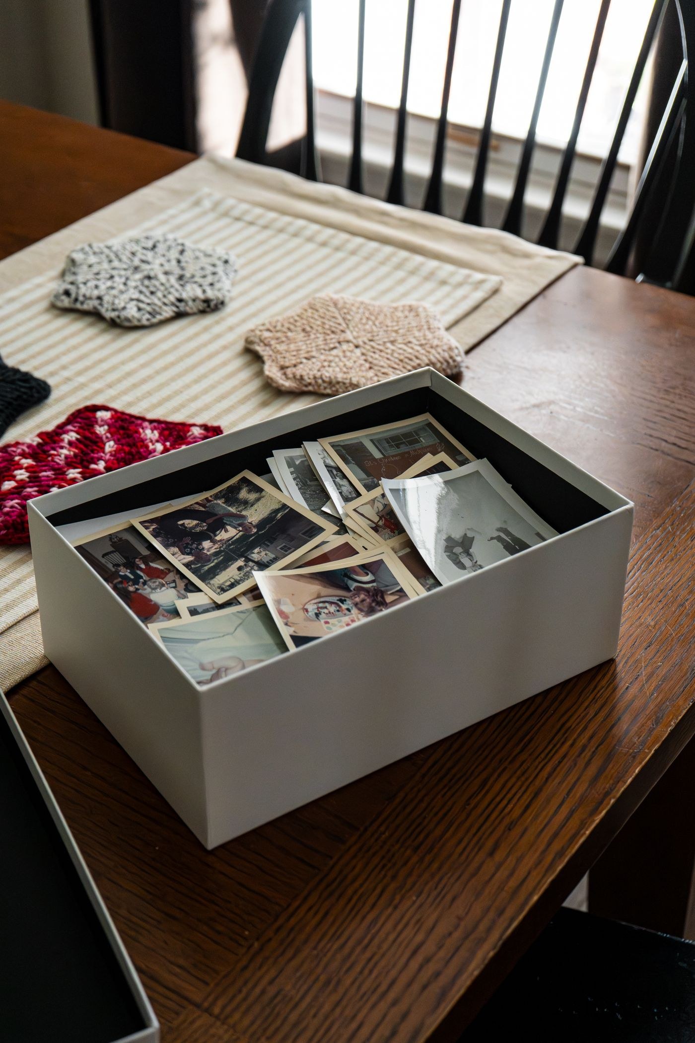 Box of loose photographs on a wooden table